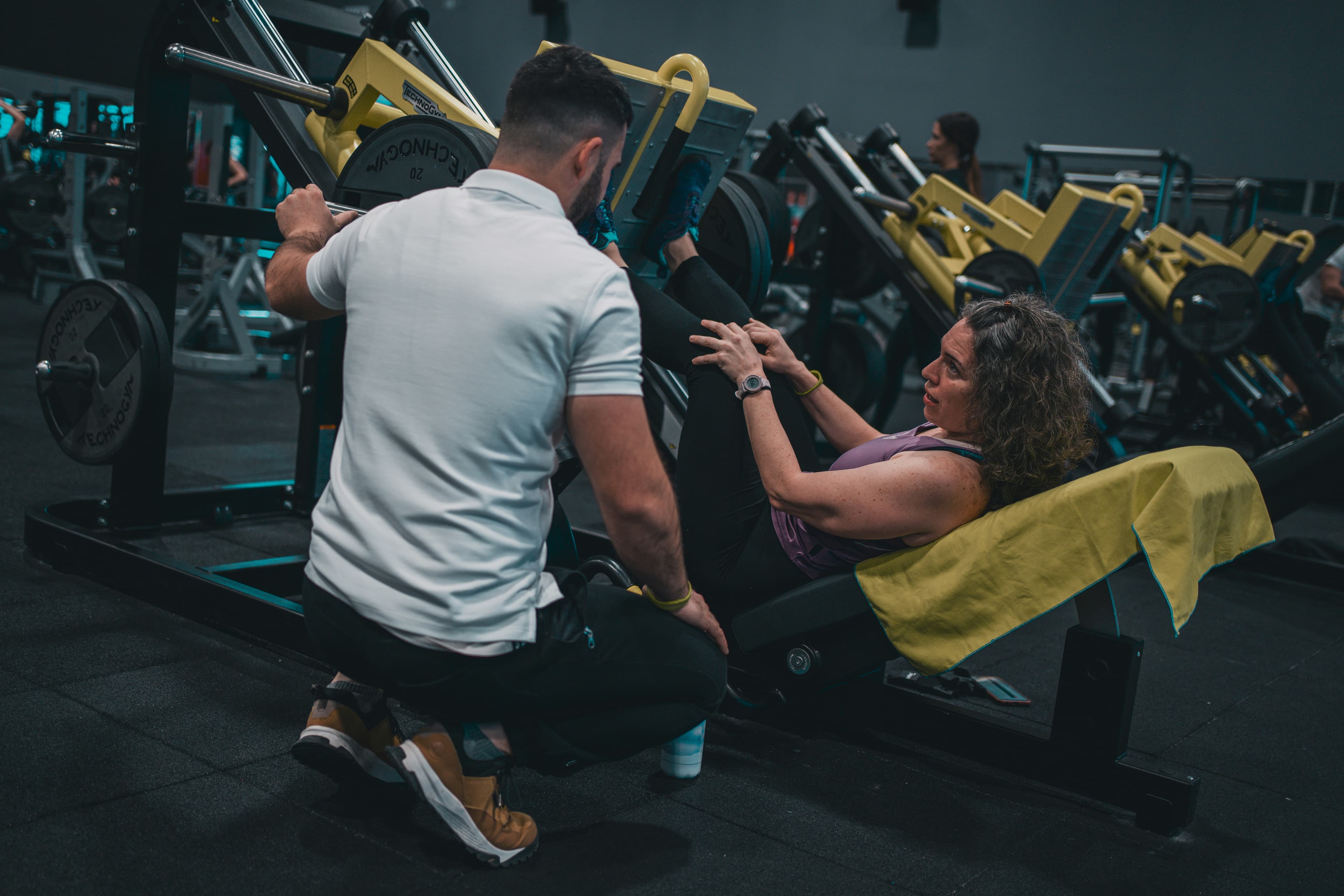 A trainer helping a client use a leg press machine